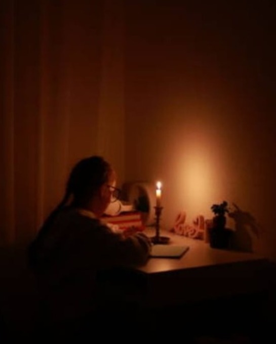 Copil studiind la lumina unei lumânări